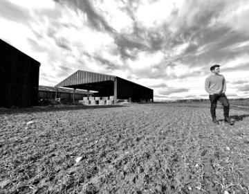 A black and white photo of Jonny McMillan walking on the Kythe Distillery site